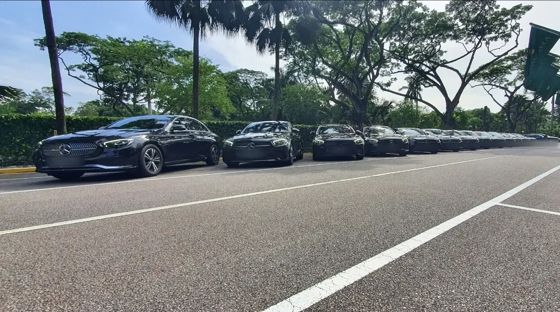 A long line of identical black Mercedes-Benz sedans waiting in a Singapore hotel driveway