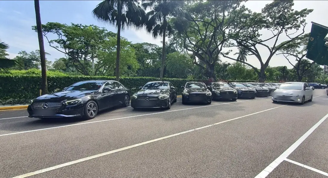 Black Mercedes-Benz E-Class sedans staged in a hotel driveway in Singapore by day, plates blurred