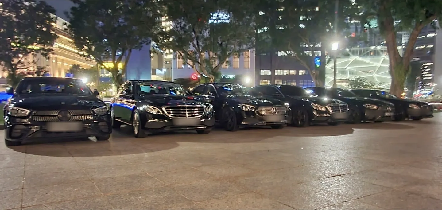 Black Mercedes-Benz E-Class sedans lined up at night in Singapore