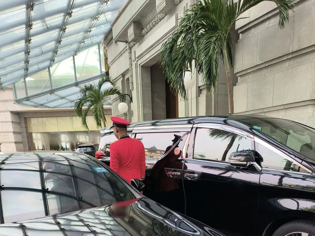 Black Toyota Alphard at a Singapore hotel entrance with a doorman opening the door