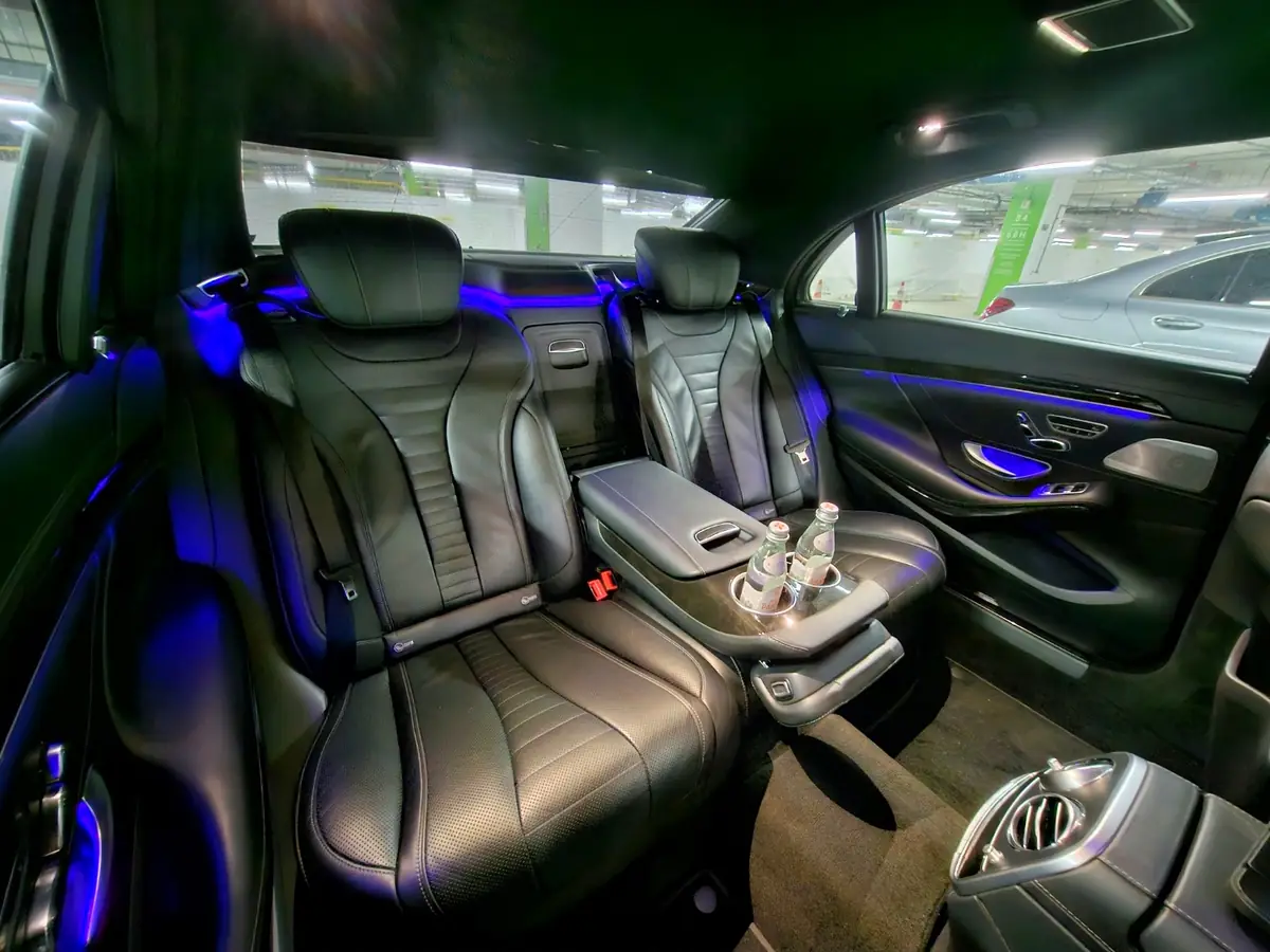 Rear cabin of an Otomobiru Mercedes-Benz S-Class with executive seats and ambient lighting